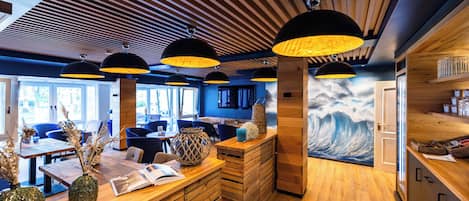 A modern interior with wooden floors, a reception desk, and a wave-themed mural.