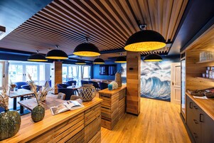 Um interior moderno com piso de madeira, um balcão de recepção e um mural com tema de ondas.