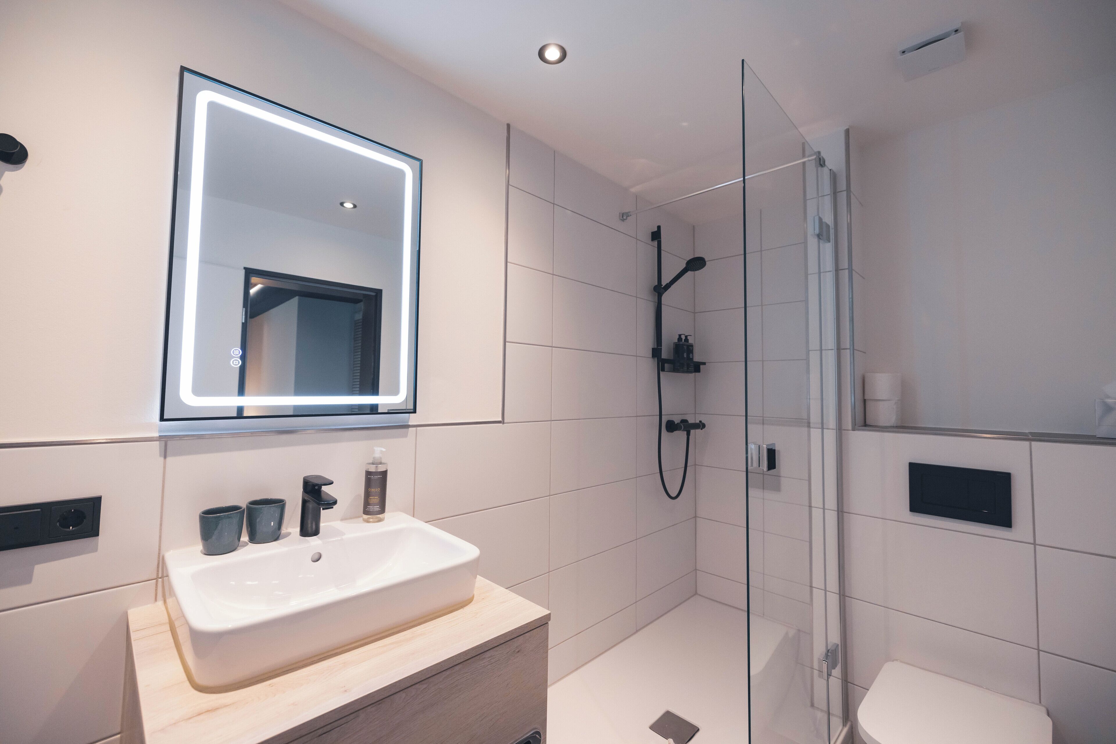 A modern bathroom with a large mirror, a sink, and a shower.