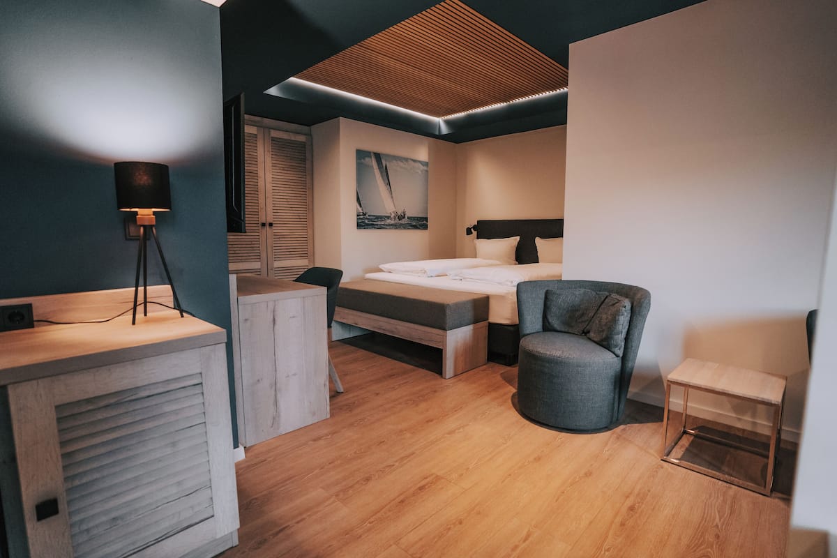 A modern bedroom with a bed, bedside table, chair, and a desk with a lamp.