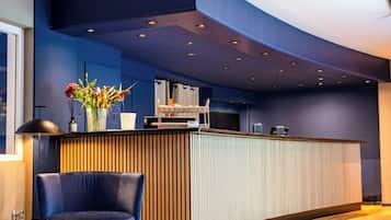 A modern bar area with a curved counter, a blue chair, and a vase of flowers.