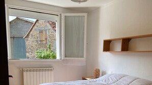 A bedroom with a bed, a window, a radiator, a chair, and a shelf. - Country house with large private courtyard. Pets welcome. (LANUEJOULS)