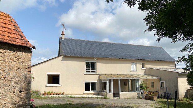 A two-story house with a covered patio, stone wall, and a garden area. - Country house with large private courtyard. Pets welcome. (LANUEJOULS)