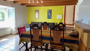 A dining area with a wooden table and chairs, a yellow wall, and a window with a view. - Country house with large private courtyard. Pets welcome. (LANUEJOULS)