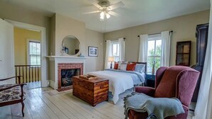 A bedroom with a fireplace, a bed, a chair, and a large mirror. - Sweet Farm on Seneca Lake (Himrod)