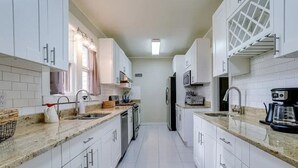 A narrow kitchen with white cabinets, a granite countertop, and a microwave. - Sweet Farm on Seneca Lake (Himrod)