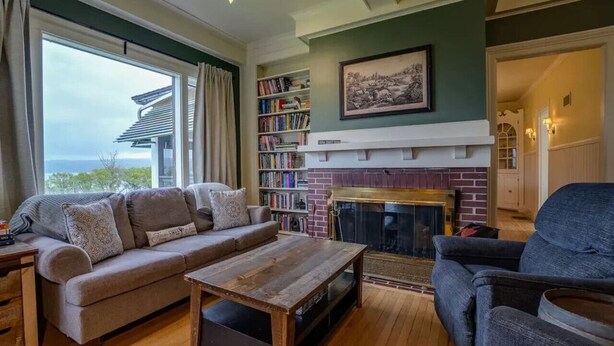 A cozy living room with a fireplace, a sofa, a coffee table, and a bookshelf. - Sweet Farm on Seneca Lake (Himrod)
