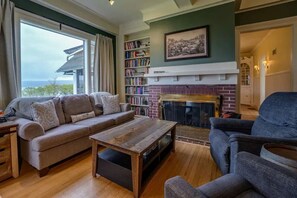 A cozy living room with a fireplace, a sofa, a coffee table, and a bookshelf.