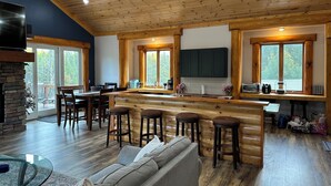 Une cuisine spacieuse dotée d’un îlot central, d’un plafond en bois et de grandes fenêtres.