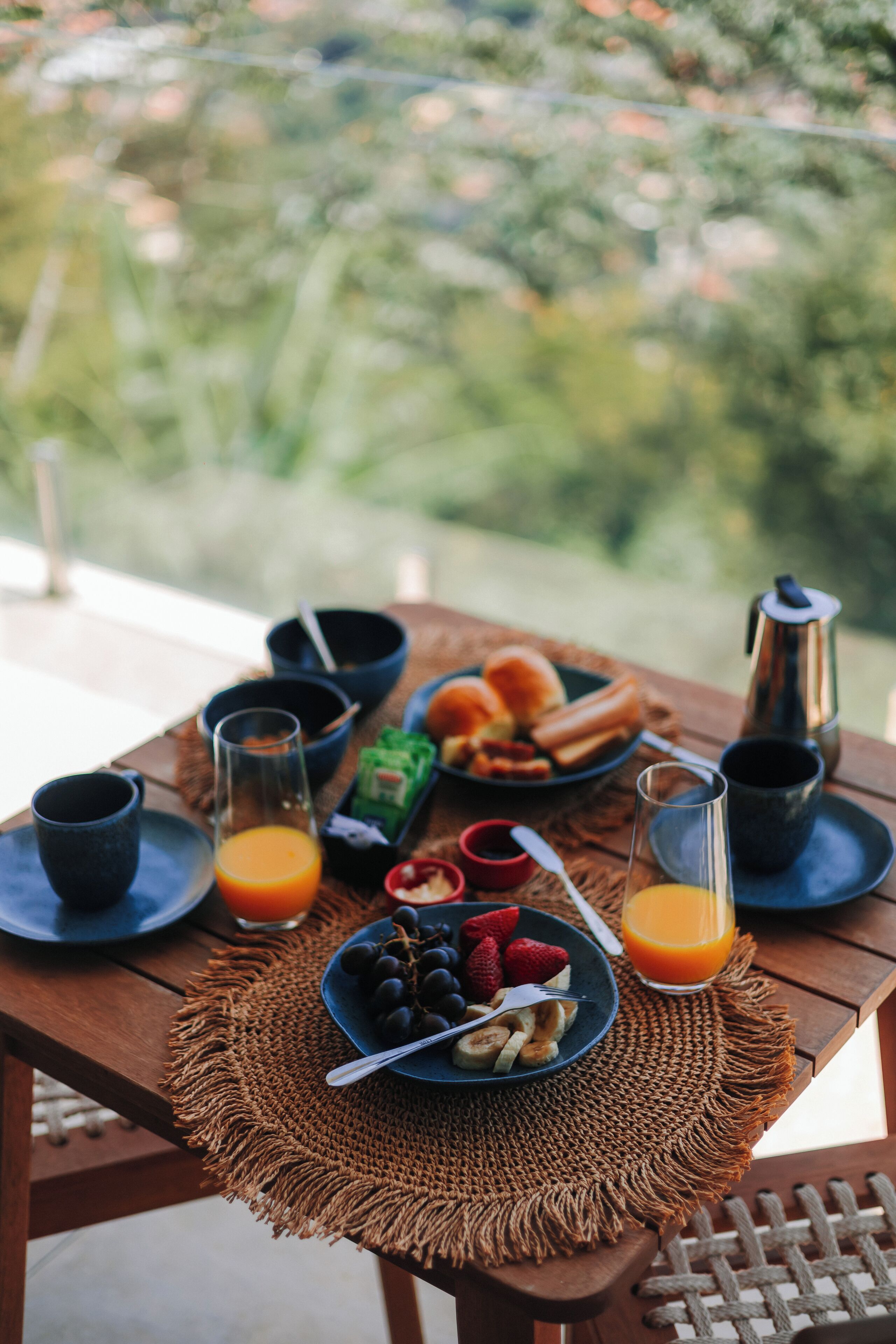 Une table de petit-déjeuner avec des assiettes remplies de nourriture, des verres de jus d’orange et une cafetière.