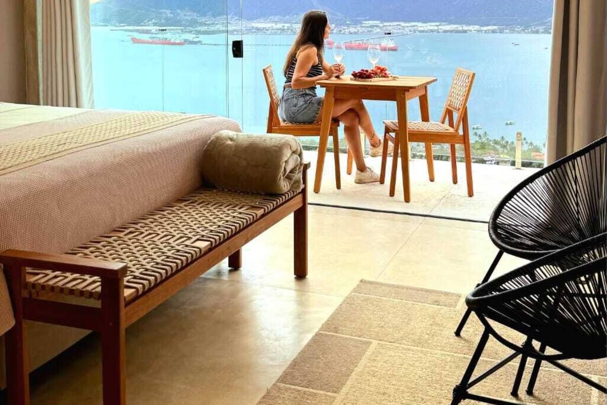 Una habitación con una cama, una mesa de comedor y vistas a un cuerpo de agua y montañas.