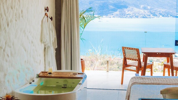 Une salle de bain moderne avec une baignoire, une douche et une vue sur la mer.