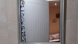 A bathroom with a white sink, a mirror, and a small vase with flowers. - 3 Bed House - Sleeps 6 - Garden - Parking - Wifi (Lusaka)