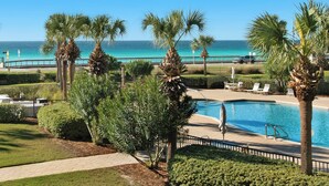 A pool area with palm trees, a view of the ocean, and a paved walkway. - Fantastic Condo at Mediterranea (Miramar Beach)
