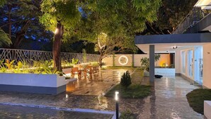 En moderne udendørs terrasse med træterrasse, siddepladser og et rundt lyselement.