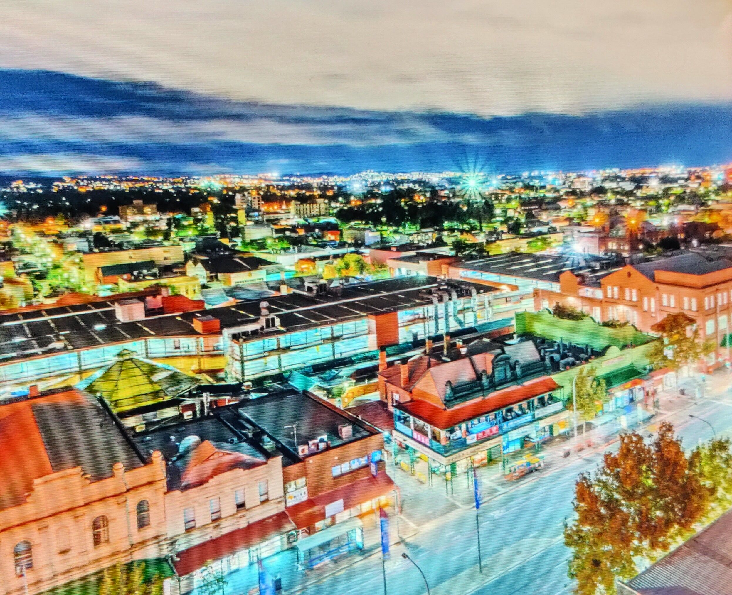 An aerial view of a cityscape with various buildings, streets, and a distant light source.