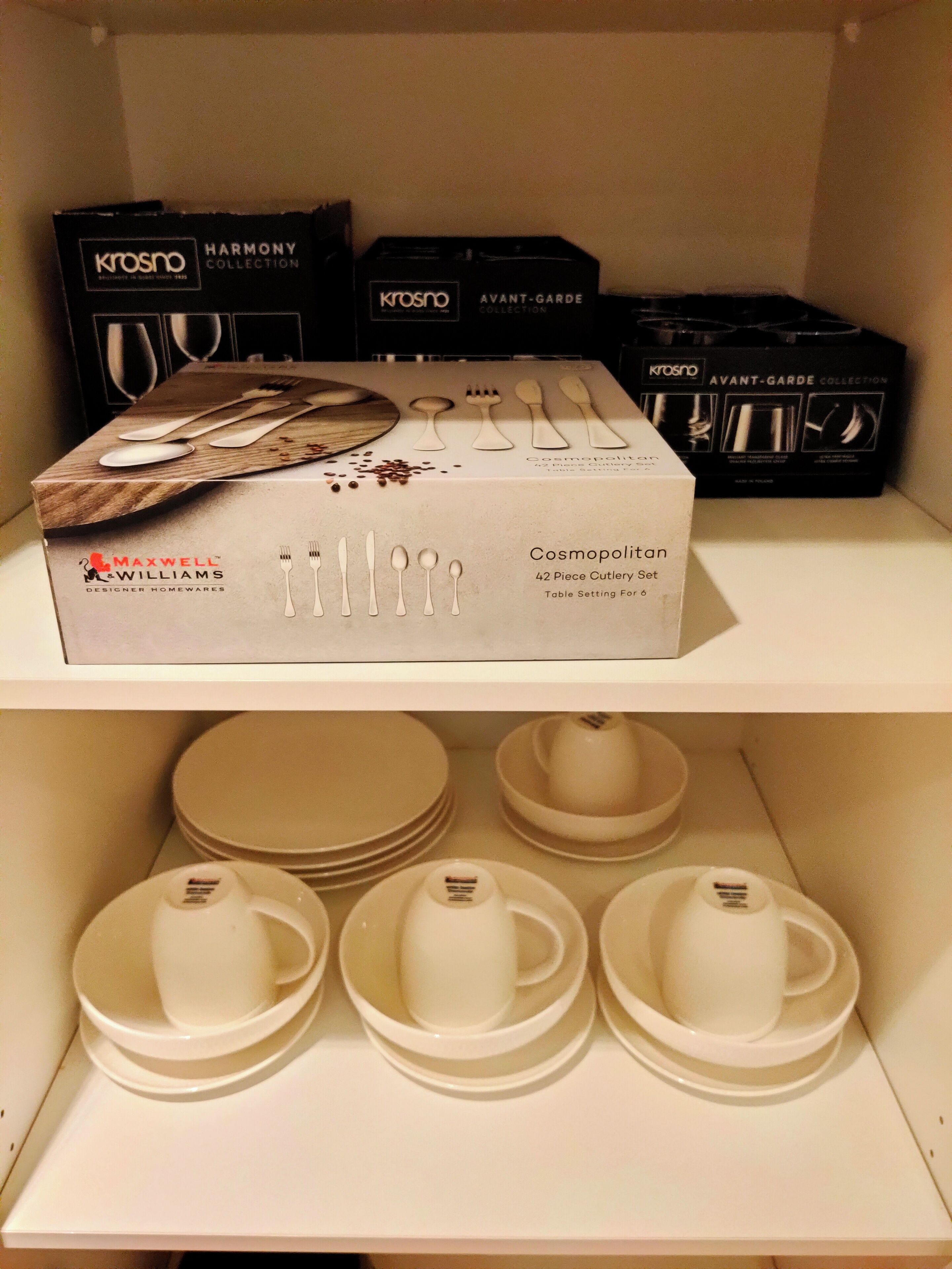 A shelf with a box of cutlery set and plates.