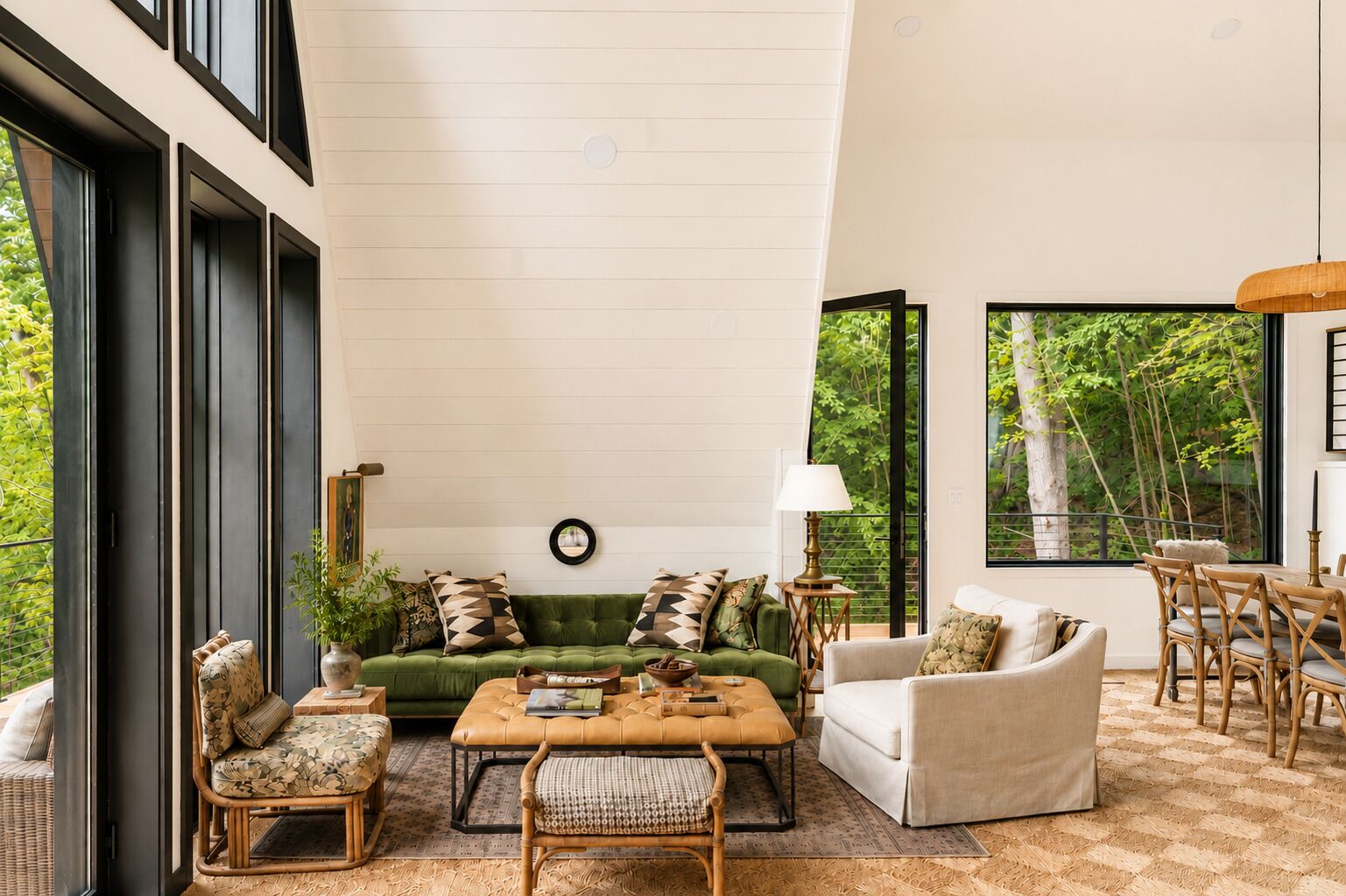 A spacious living room with a green sofa, a white armchair, and a coffee table. There is a dining area with a table and chairs.