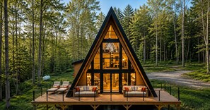 A modern cabin with a triangular roof, wooden deck, and outdoor seating area. - A Soulful A-Frame Retreat with a Hot Tub (Margaretville)