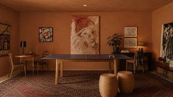 Una stanza con un tavolo da ping pong, sedie, un tappeto e opere d'arte alle pareti.