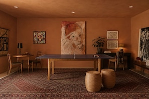 Habitació amb taula de ping-pong, cadires, una catifa i obres d'art a les parets.