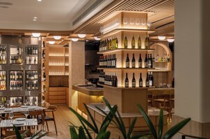 Un restaurante con barra de vinos, estantes de madera con botellas y un diseño de interiores moderno.
