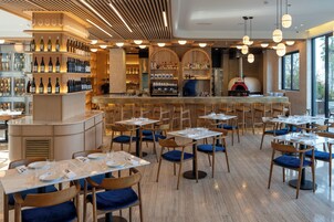Un restaurante con zona de bar, sillas y mesas de madera.