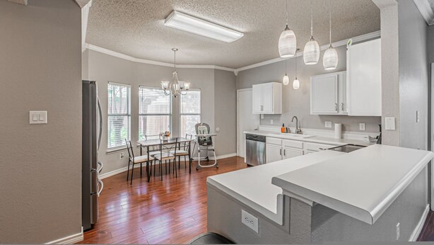 A modern kitchen with white cabinetry, a central island, and pendant lighting. - Lux 3-br Garage Gated Yard by The Star Frisco (Frisco)