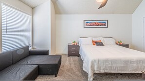 A bedroom with a bed, a nightstand, a dresser, a sofa, and a ceiling light fixture. - Lux 3-br Garage Gated Yard by The Star Frisco (Frisco)