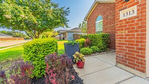 A brick building with a number '1313' on the side, surrounded by well-maintained landscaping and a clear sky.
