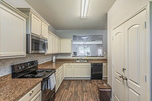 A kitchen with white cabinets, a stainless steel microwave, a black stove, and a dishwasher. - Spacious 5BR Dallas Retreat Perfect for Business Travelers Families (Dallas)