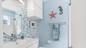 A bathroom with a white sink, a round mirror, a toilet, and a towel rack with a blue towel.