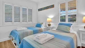 A room with two beds, white walls, and a beach-themed sign.