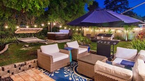 An outdoor patio area with wicker furniture, a barbecue grill, and string lights.
