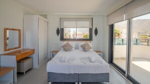 Un dormitorio moderno con una cama grande, un escritorio y un ventanal con vistas a la ciudad.