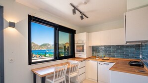 Una cocina compacta con comedor, vista al mar y salpicadero de azulejos.