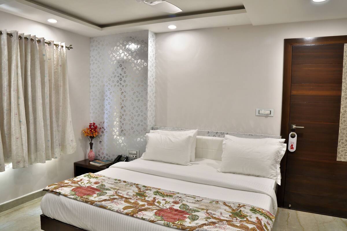 A neatly arranged bedroom with a bed, a nightstand, a vase with flowers, and a door with a lock.