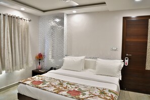 Une chambre à coucher bien rangée, avec un lit, une table de chevet, un vase de fleurs et une porte dotée d’une serrure.