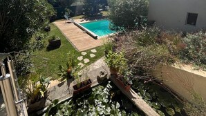 A backyard with a swimming pool, a wooden deck, and a garden with various plants and a pond. - Air-conditioned house in a fully renovated farmhouse 5' from the Ardèche. (Saint-Julien-de-Peyrolas)