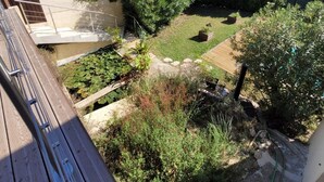 A garden with a wooden deck, various plants, and a view of the countryside. - Air-conditioned house in a fully renovated farmhouse 5' from the Ardèche. (Saint-Julien-de-Peyrolas)