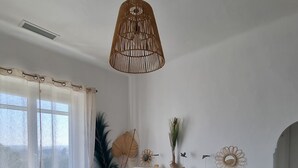 A cozy living room with a wooden coffee table, a sofa with cushions, a hanging rattan light fixture, and a window with sheer curtains. - Air-conditioned house in a fully renovated farmhouse 5' from the Ardèche. (Saint-Julien-de-Peyrolas)