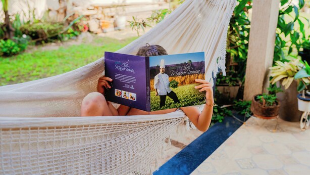 Une personne se détend dans un hamac à l’extérieur, en lisant un livre.