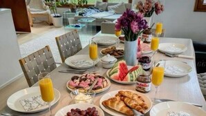 Une table dressée pour le petit-déjeuner, avec des assiettes remplies de nourriture, notamment des crêpes, des fraises et des croissants, ainsi que du jus et de la confiture.