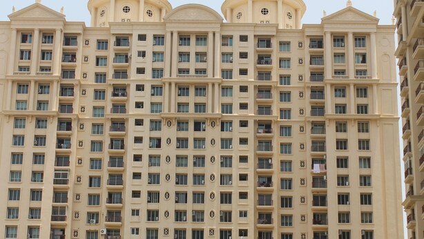 Un immeuble de grande hauteur à la façade symétrique, doté de nombreuses fenêtres et de deux imposantes structures en forme de dôme au sommet.