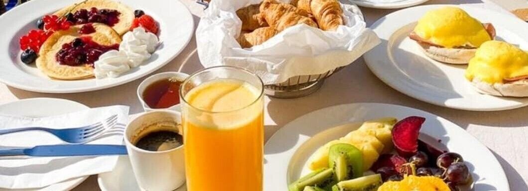 A breakfast setting with pancakes, croissants, and a glass of orange juice.
