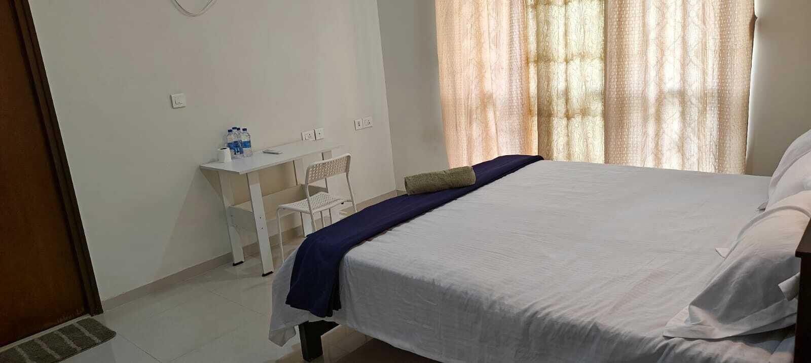 Quarto com cama, escrivaninha e cadeira.
