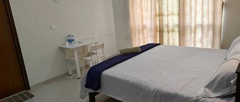 Quarto com cama, escrivaninha e cadeira.
