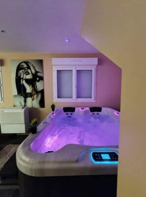 Relax in a serene spa room with a large hot tub and digital control panel.