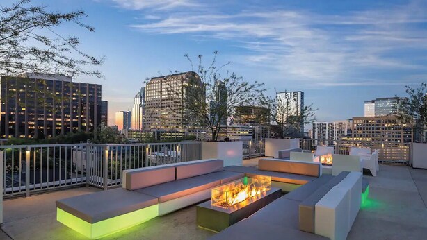 An outdoor seating area with a fire feature, surrounded by modern buildings and a clear sky. - Wyndham Resort 1BD/1BA Deluxe Suite in fantastic downtown Austin - RACE WEEKEND! (Austin)