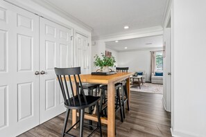 A dining area with a wooden table, black chairs, and a vase with green plants.